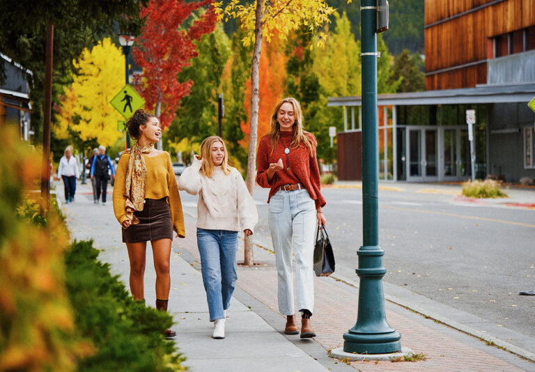 Three women walk down a sidewalk together