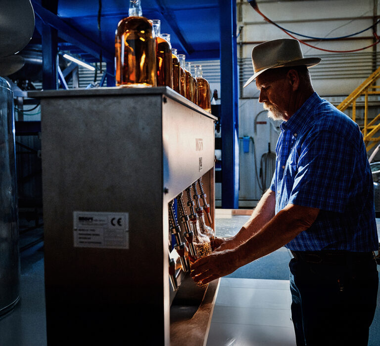 A man fills two bottles with alcohol.
