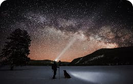 A person shines a headlamp into a starry sky