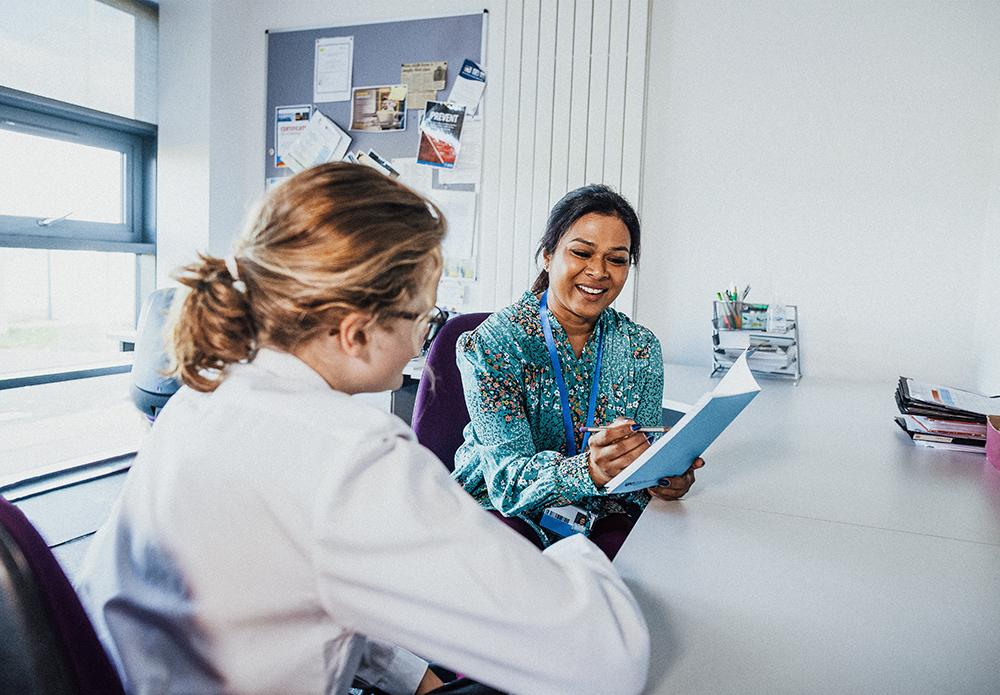 Two women review paperwork at a desk.