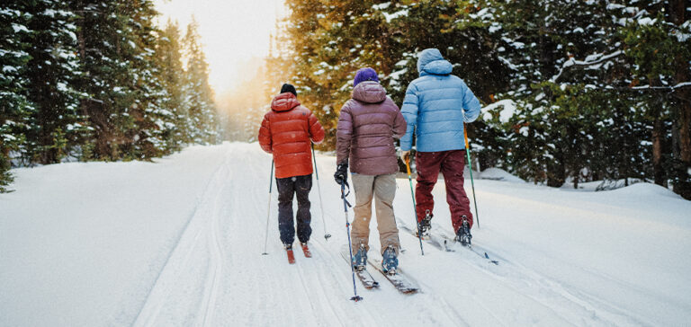 A trio of cross-country skiiers make tracks on a snow-covered trail.